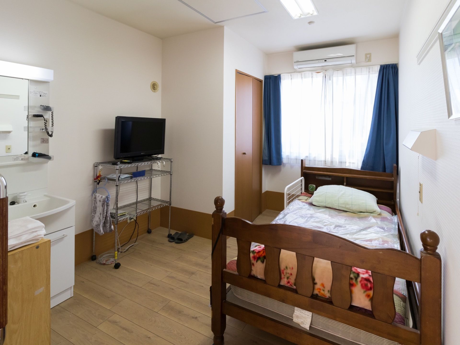 居室の窓側の壁にエアコンが設置されている。居室内には白い洗面台もあり、テレビ台などを置くスペースもある。