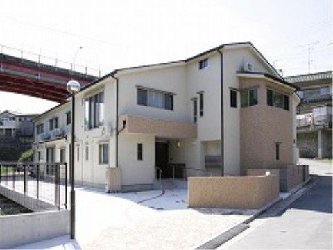 ２面が道路に面している敷地に建つ明るい色調の外壁の施設