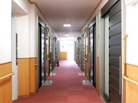 廊下は見通し良く、両サイドの壁には手すりが設置されている。居室扉は、スライド式で民家に設置されているようなしつらえで扉から自宅のようである。