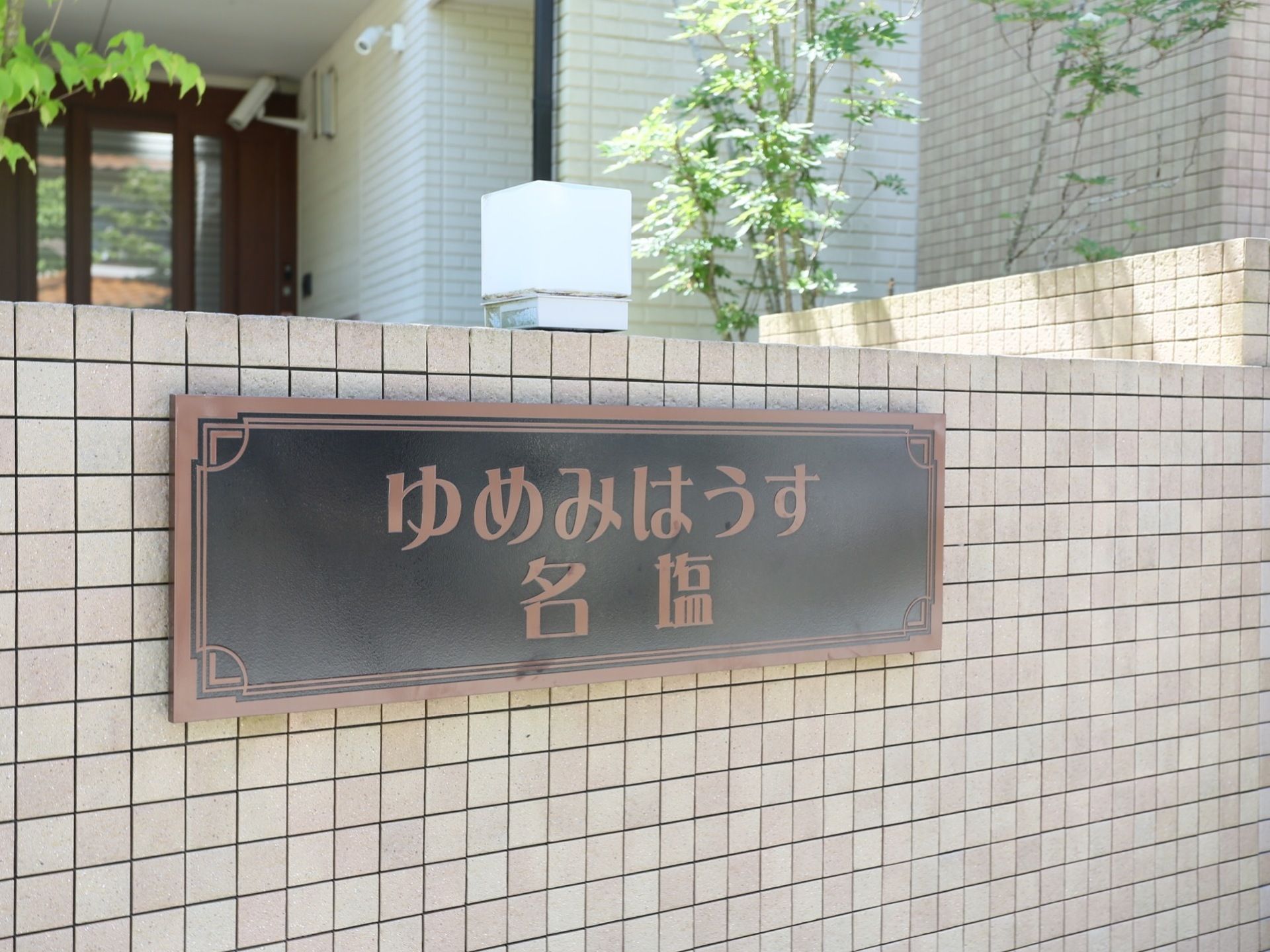 施設名の看板が外壁に設置されている。黒色のプレートに大きなブラウン色の文字で表示されているので読みやすい。