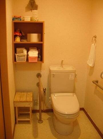 手すりが付いたトイレにはオープンタイプの棚があり、タオル掛けも設置されている。