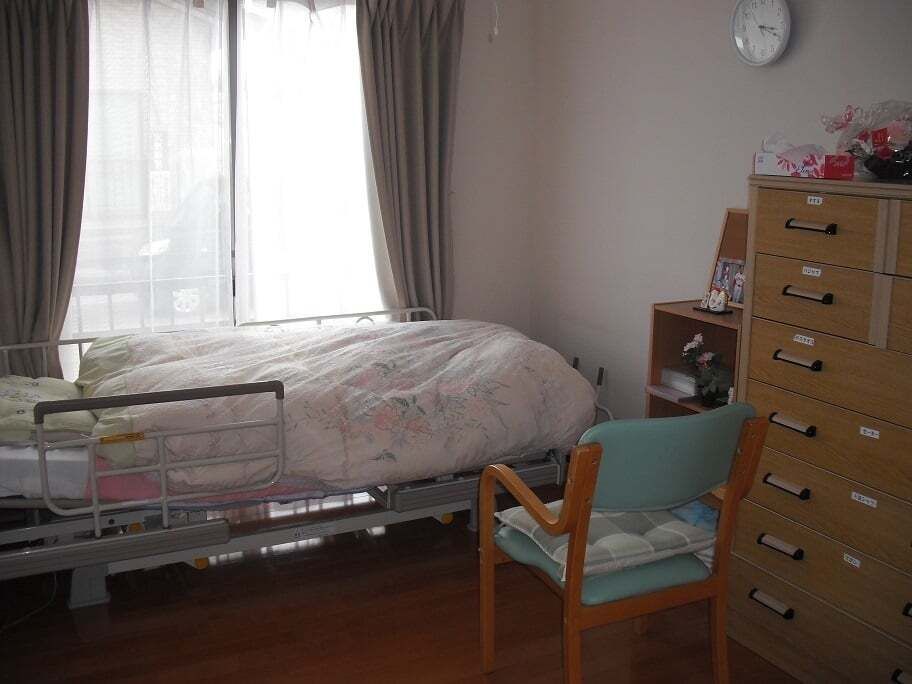 ラベリングされたタンスや寝具付きのベッド、大きな窓が付いた部屋にはいすも置かれている。