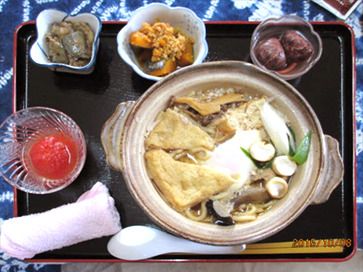 キノコや野菜、揚げが乗った鍋焼きうどん。かぼちゃのそぼろ煮などもトレーの上にある。