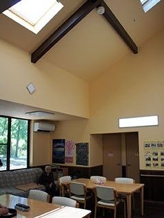 天井が高いハリが見えるデザインのスペース。いすやテーブルが置いてある食堂のようなスペース