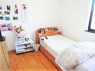壁に写真類が飾ってある居室内の様子。ベッドや小物入れなど日用品が置いてある部屋