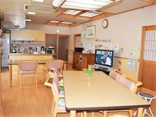 奥には冷蔵庫やキッチンがあり、手前にはテレビやダイニングテーブルが置かれてる。