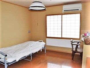 パネルヒーター付きのフローリングの居室は和風で、ベッドやテーブルセット、エアコンが置かれている。