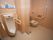通常の便器と男性用の便器が並べて置かれている広いトイレがある。床はタイル張りになっており、壁には大きな手すりが設置されている。