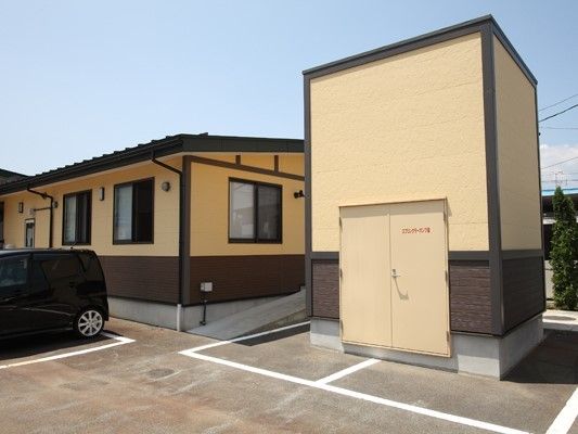 ベージュの平屋建ての建物がある敷地内の一角に大きな蔵のような建物がある。