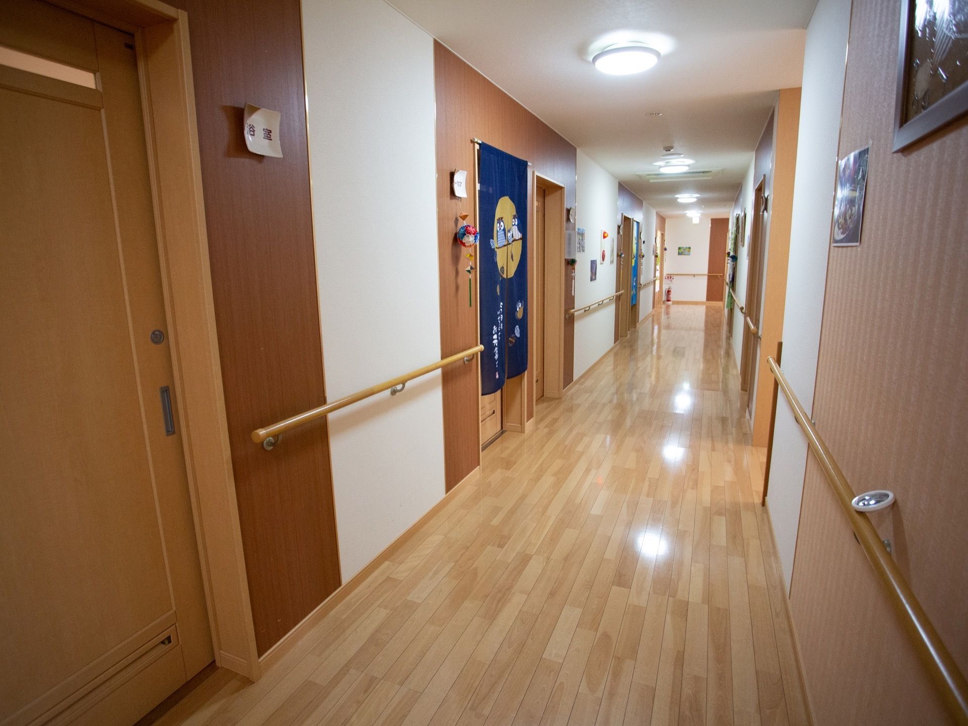 廊下は一直線に長く続いており、壁に沿って手すりが設置されている。廊下の両側に浴室などの部屋に通じるドアが並んでいる。