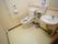 個室トイレの一例である。中央奥の角に温水洗浄便座があり、奥の壁には固定式の手すりと操作パネルが設置されている。