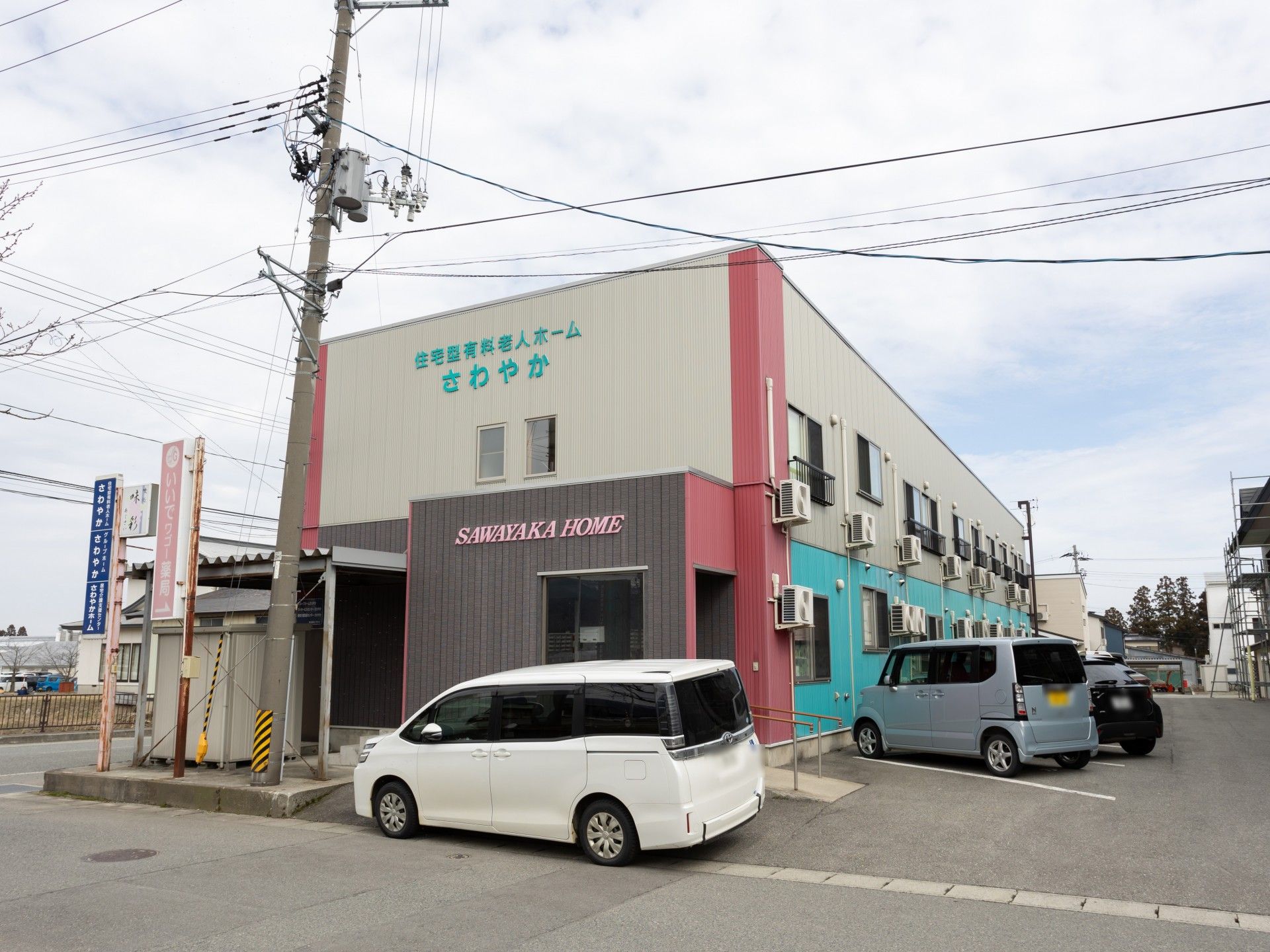 日当たりのいい場所で話しているカーディガンを着た高齢女性とエプロンを付けた女性スタッフ。