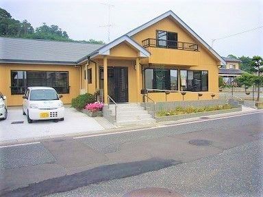 一部2階建ての建物。駐車場や玄関に階段・スロープも付き明るい雰囲気。