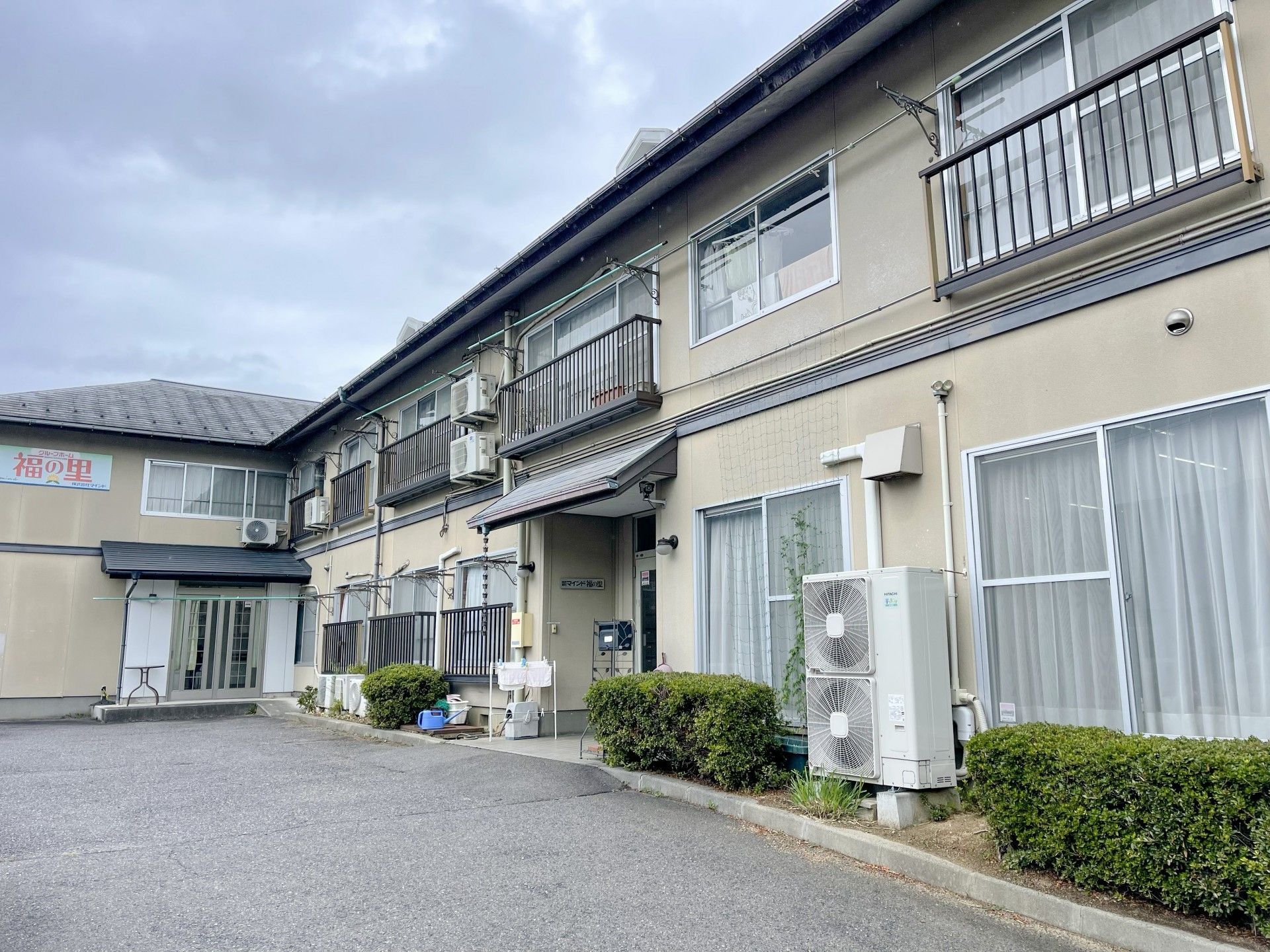ベージュを基調とした建物がある敷地内には駐車スペースもあり、玄関先には屋根も付いている。