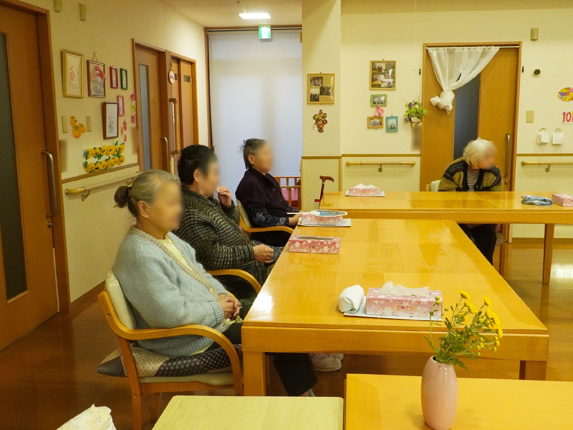 車いすに乗った女性を押す家族の男性とそこに寄り添う介護スタッフの様子