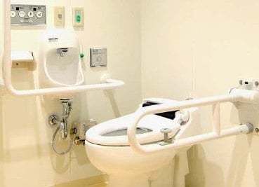 手すりがついている施設内のトイレの様子。固定式の上手な手すりと緊急コールが写っている