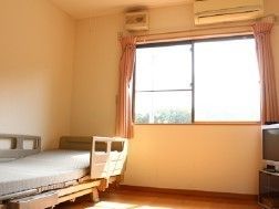 窓付きの明るいワンルームタイプの部屋。エアコン、ベッドなど日用品が取り付けられている