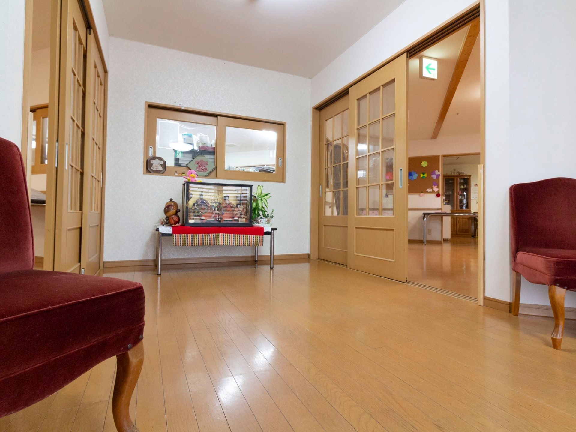 部屋へと続くホールの様子である。窓の奥にスタッフルームが見える。その下には雛人形がケースに入れられて、豪華に飾られている。