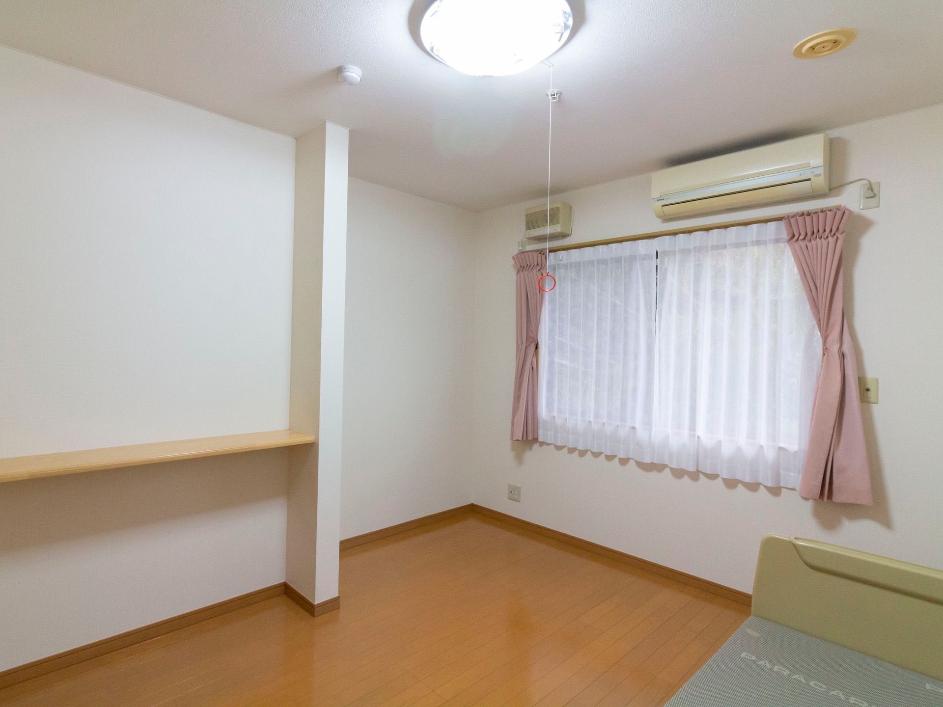 白色の壁と天井で清潔感と明るさがある居室である。ベッドや空調が完備のほか、大きな窓で外光が差し込むような造りとなっている。