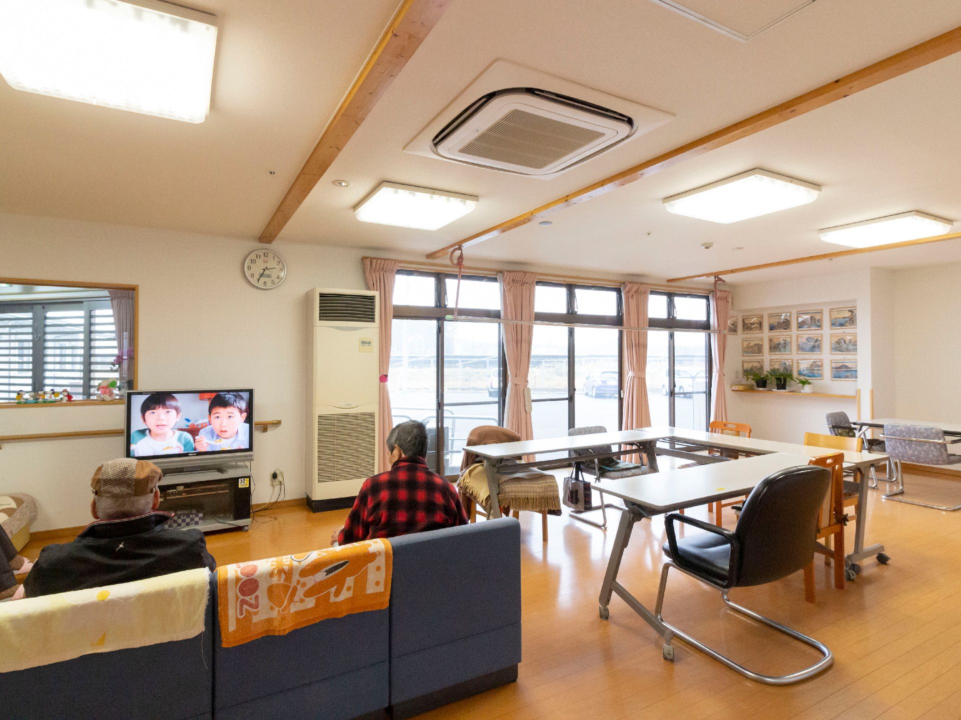 テレビやソファが完備され、大きな窓から自然光が入る明るい共有スペース