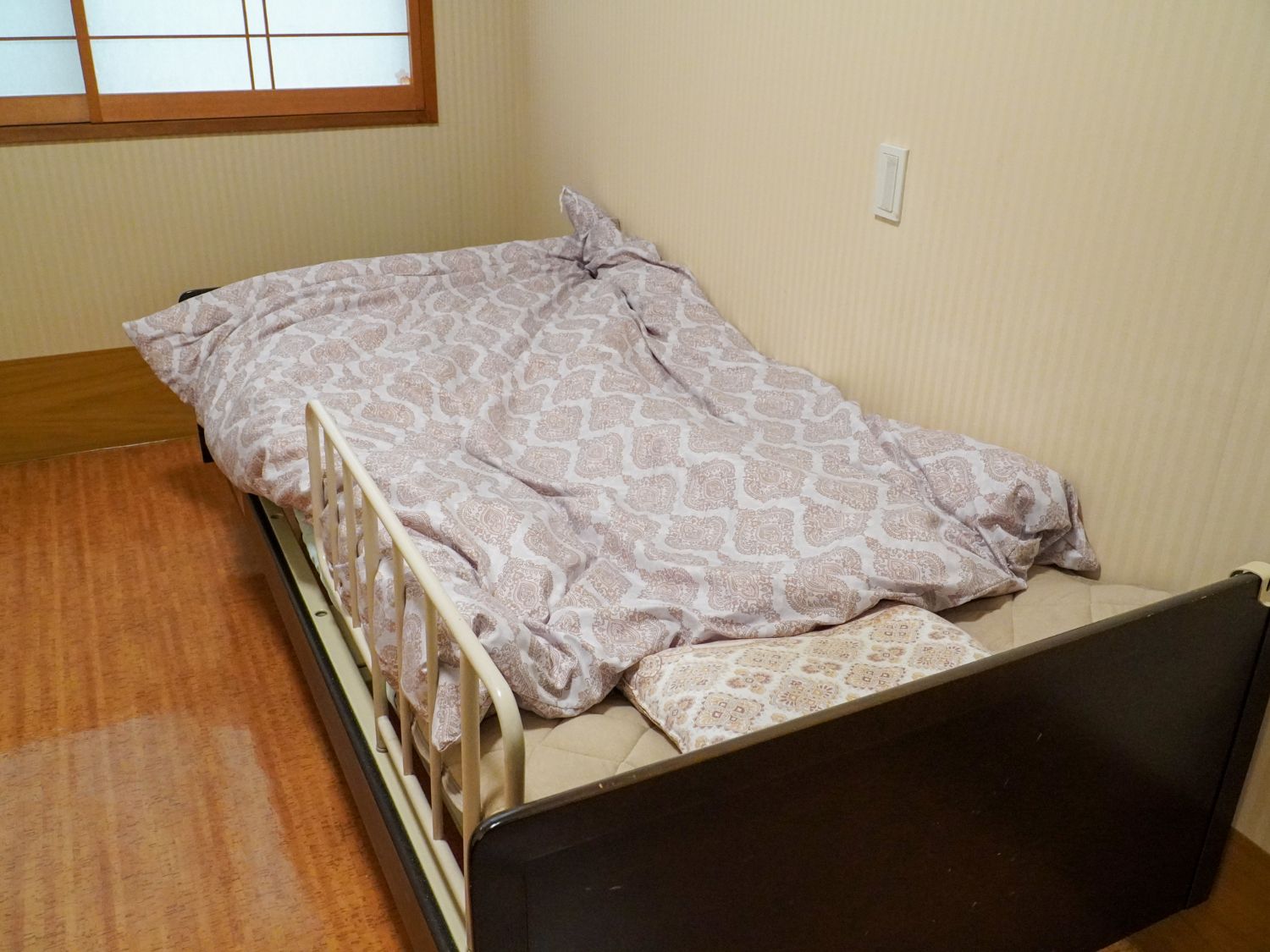 窓から日差しがあたり、介護ベッドや家具を照らしている居室