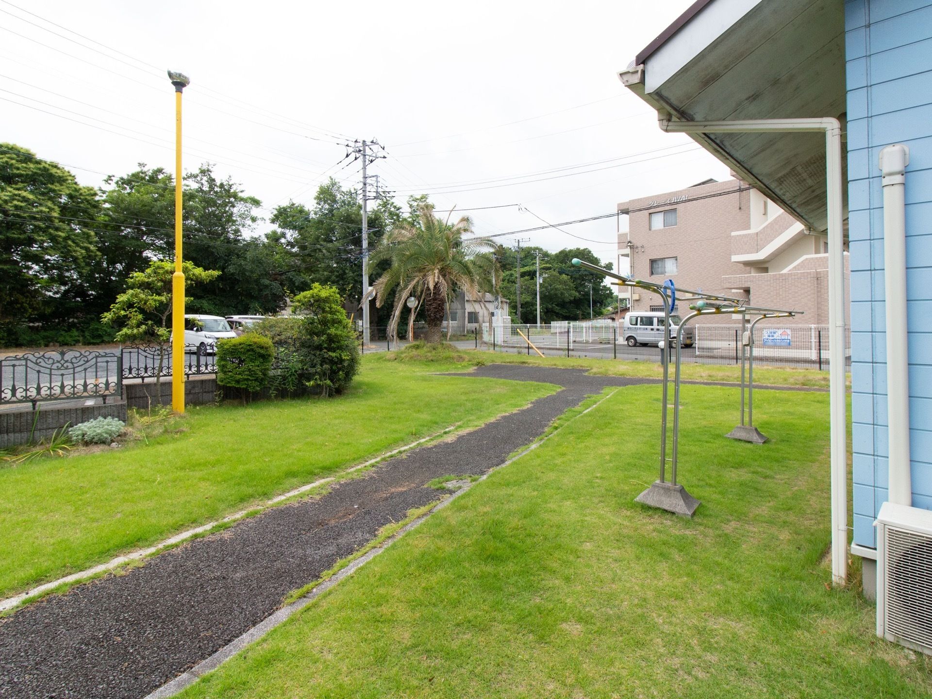 敷地内には庭が設けられており、歩道部分が舗装されている。物干しざおが置かれており、植栽が施されている。