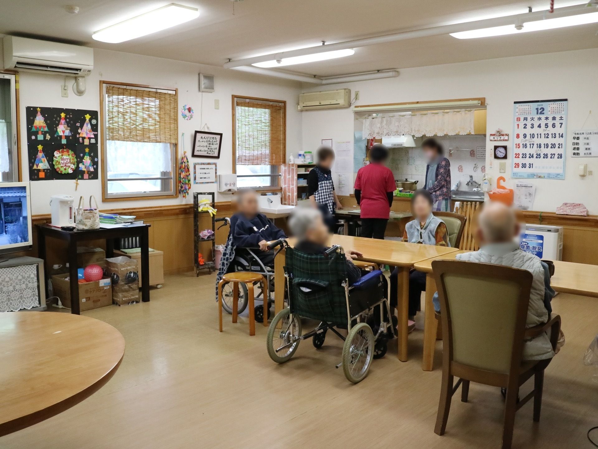 エアコンの付いた広いフロアがあり、テーブルセットが並べられている。入居者様が席についてくつろいでいる。