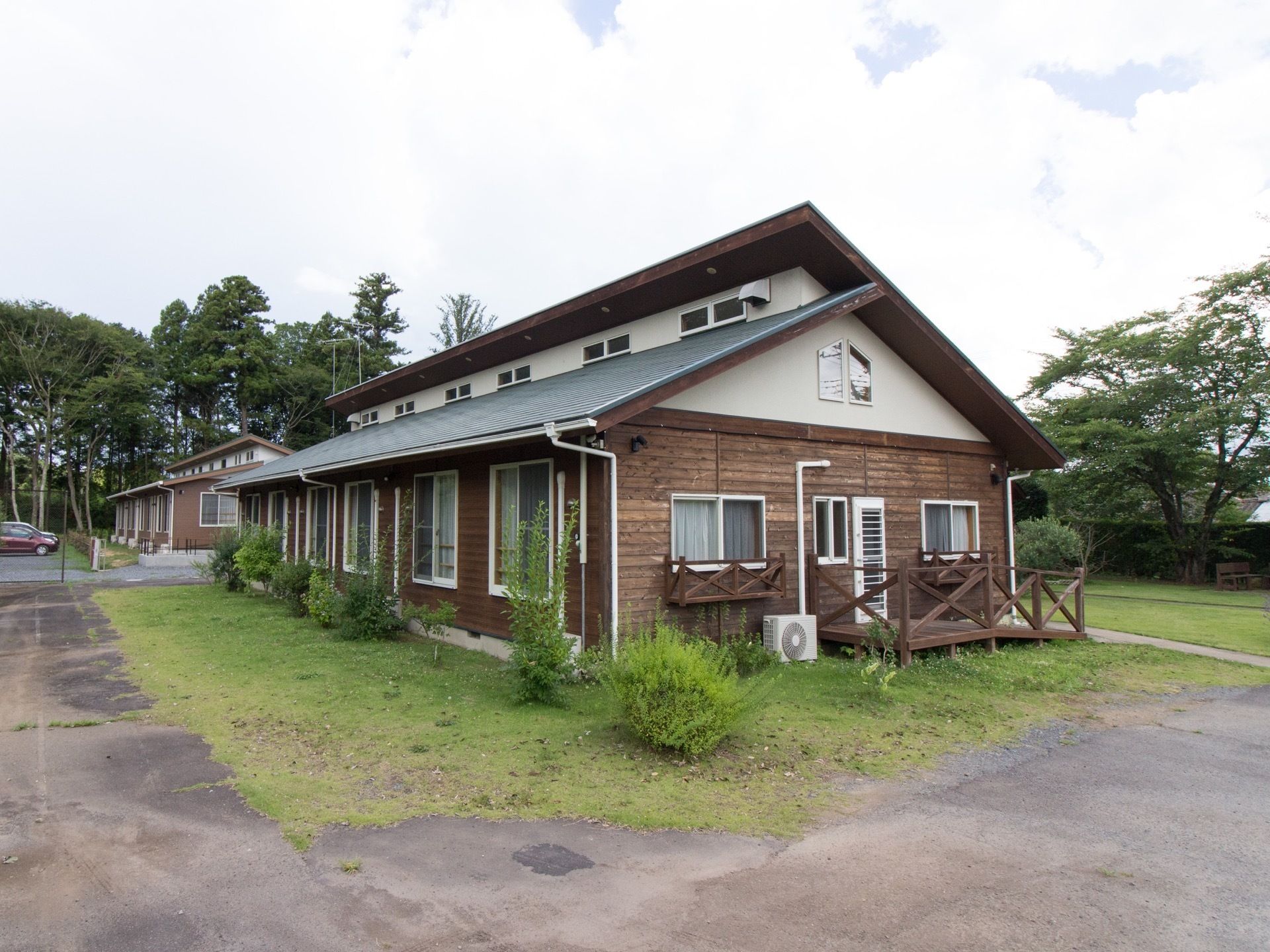 施設の建物は2階建てで、周囲には緑豊かな自然が多くある。建物の外壁やスロープ、室外機カバーなどは茶色の木目で統一されている。
