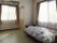 花柄の寝具がセットされたベッドやエアコンが付いた部屋にはカーテン付きの大きな窓が二つあり、収納スペースもある。