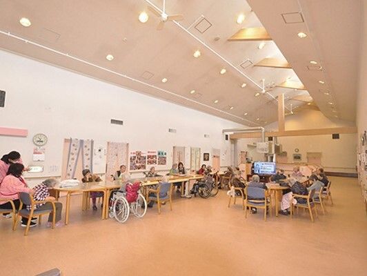 複数のダイニングテーブルが置かれた広い共有スペースは天井が高く、入居者とスタッフでにぎわっている。