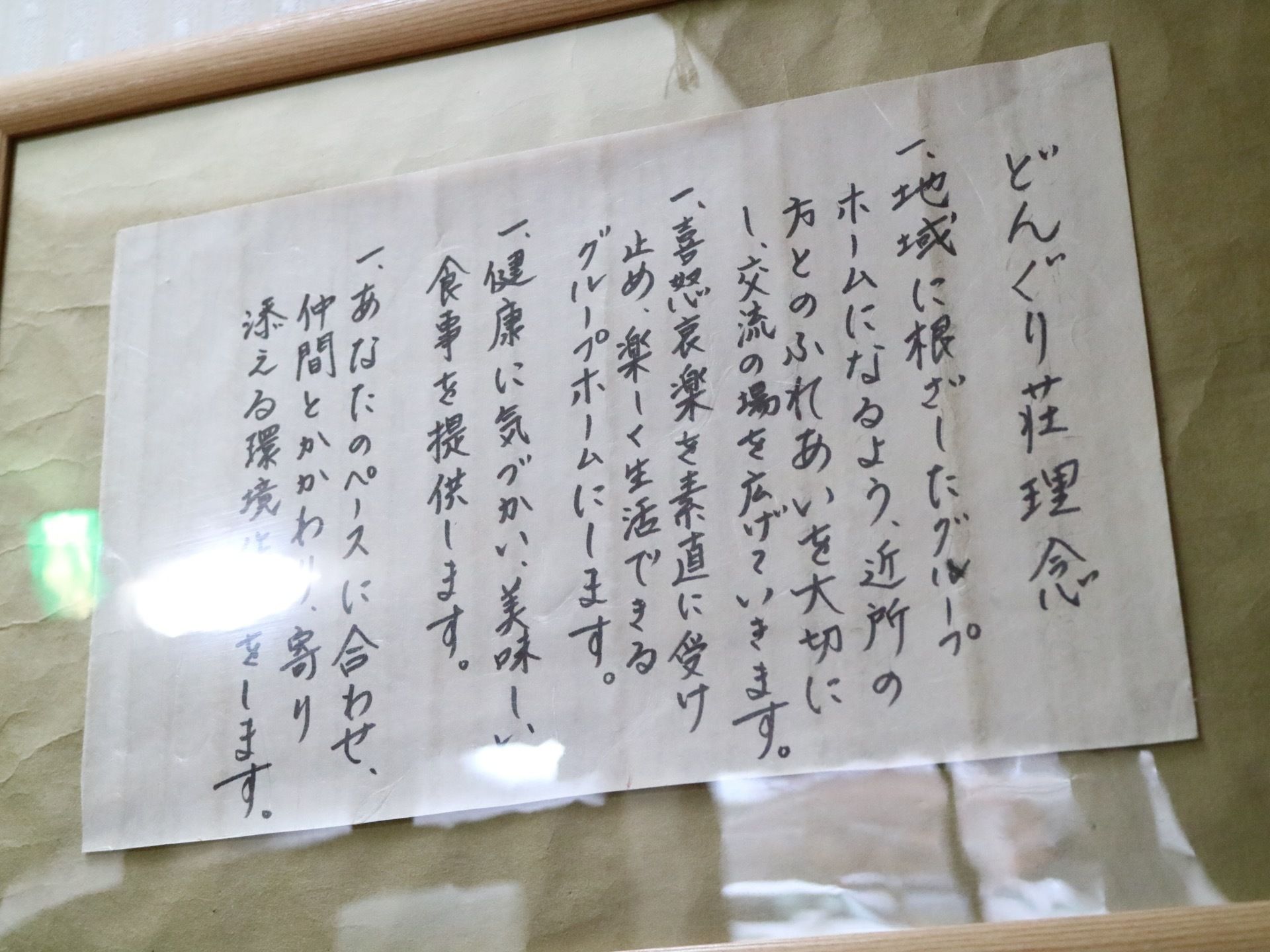 白い紙に、黒のマジックペンで施設の理念が書かれている。理念は全部で4か条書かれ、掲示板に掲示されている。