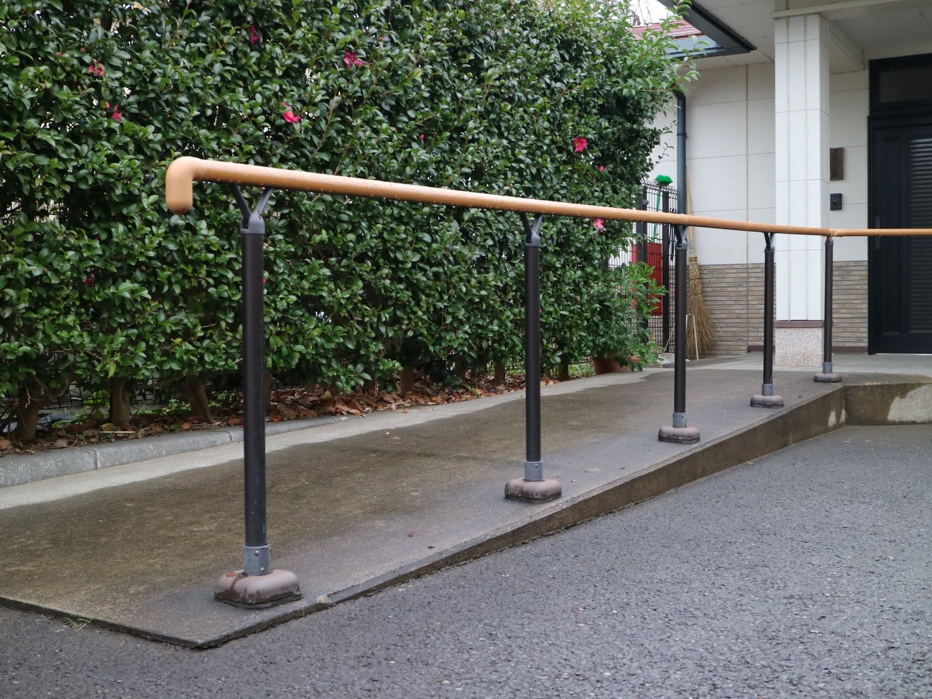 玄関へとつながる、スロープが設置されている。スロープは木目調で、地面にはコンクリートで舗装されている。