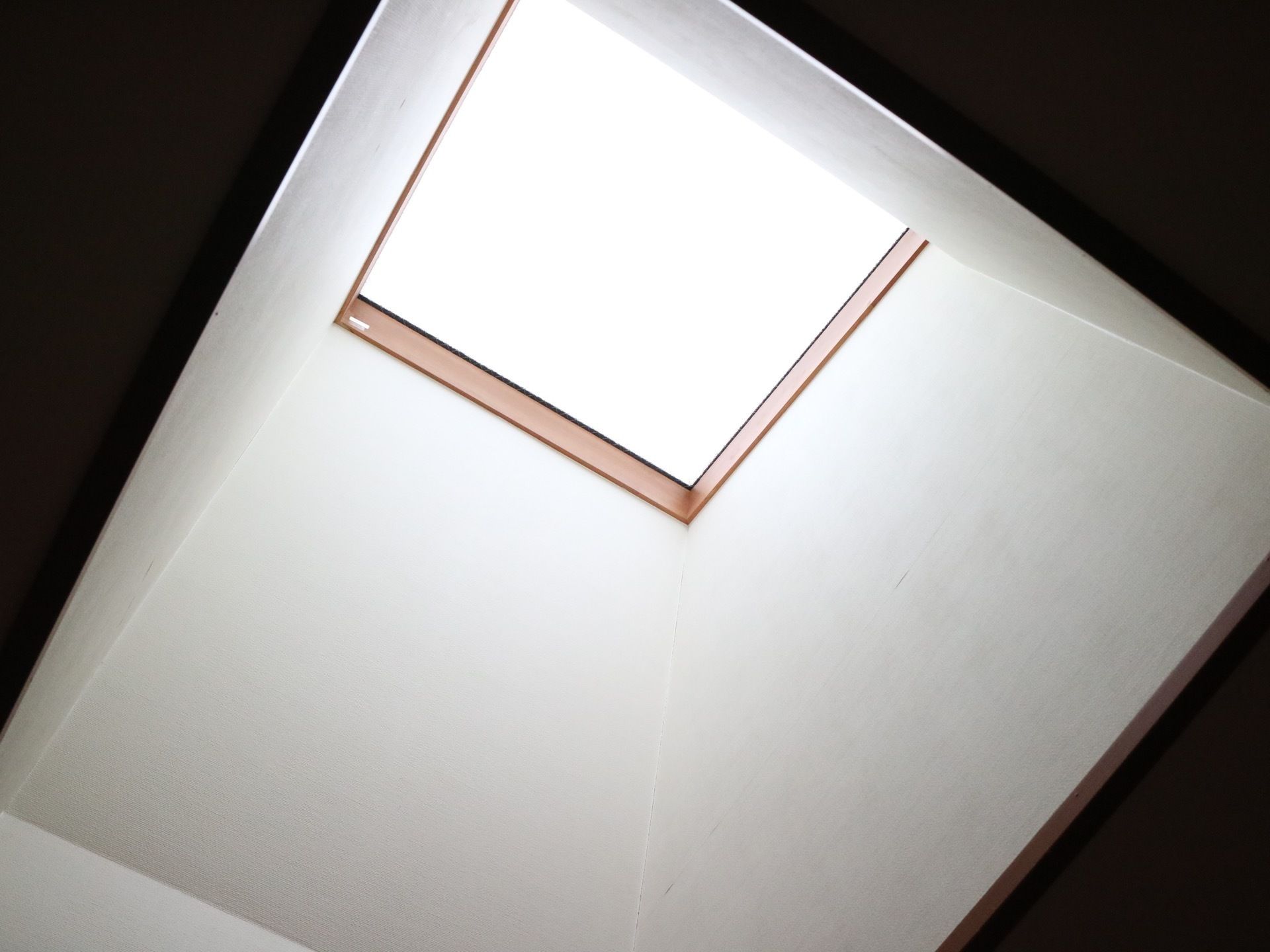 廊下の一角には、屋根まで続く高い吹き抜けと四角い窓が設置されている。窓には、木枠が取りつけられている。