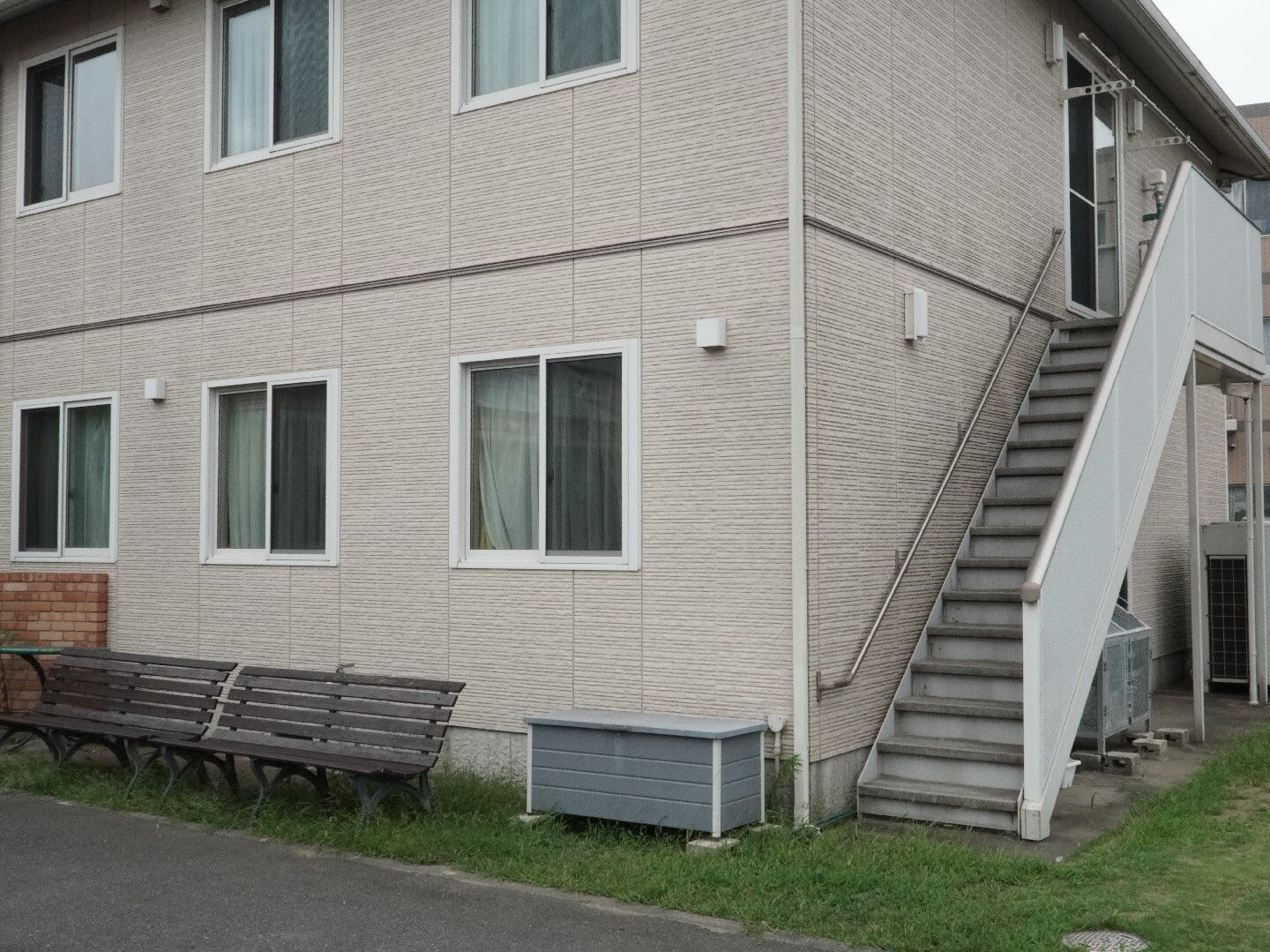 アスファルト沿いに立地しているベージュの外観で２階建ての建物