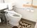 個室トイレの一例である。中央に温水洗浄便座付のトイレがあり、背もたれパッドと可動式の手すりが取り付けられている。
