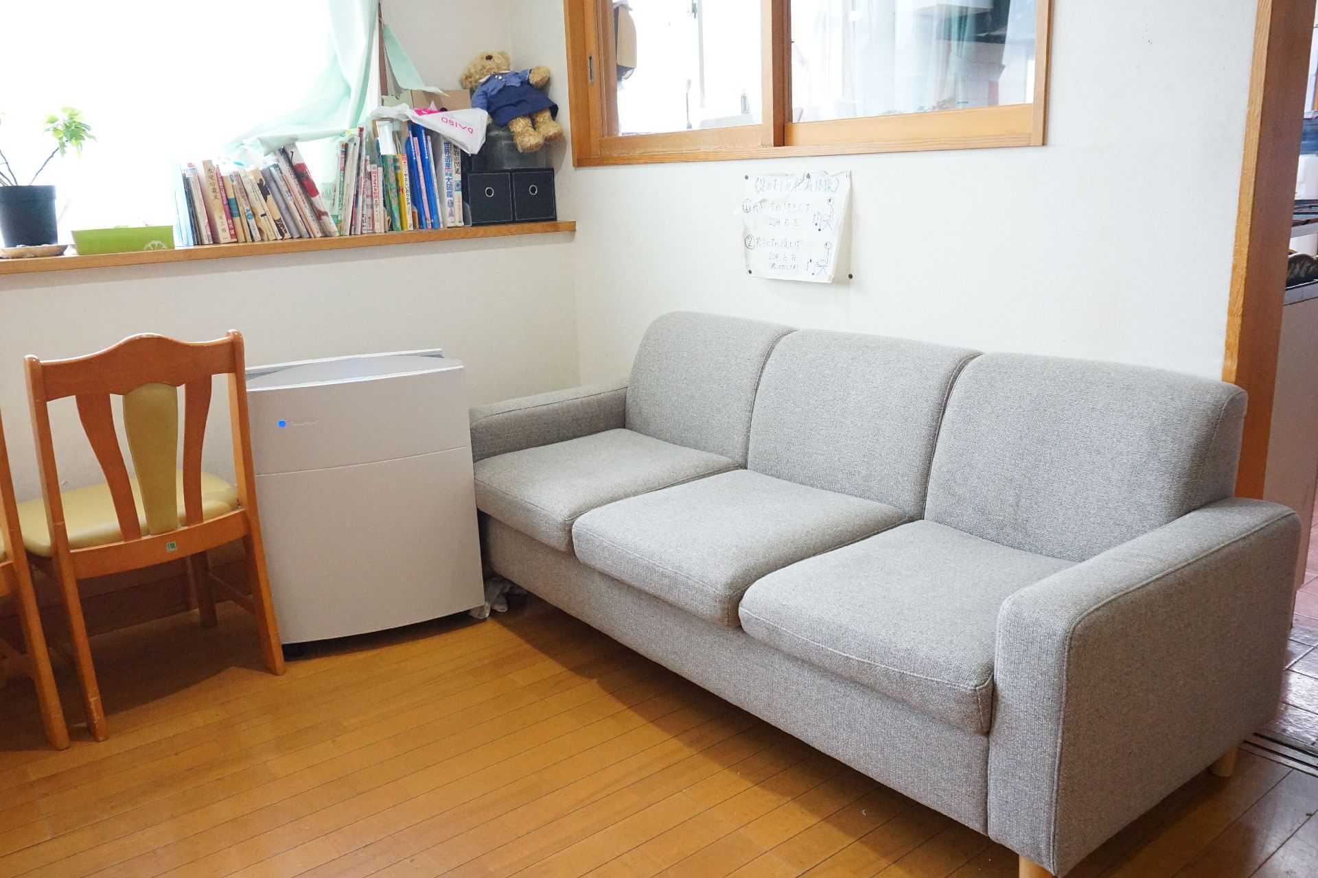 窓から陽光が入り、多人数掛けの大型ソファーが置かれているリビング
