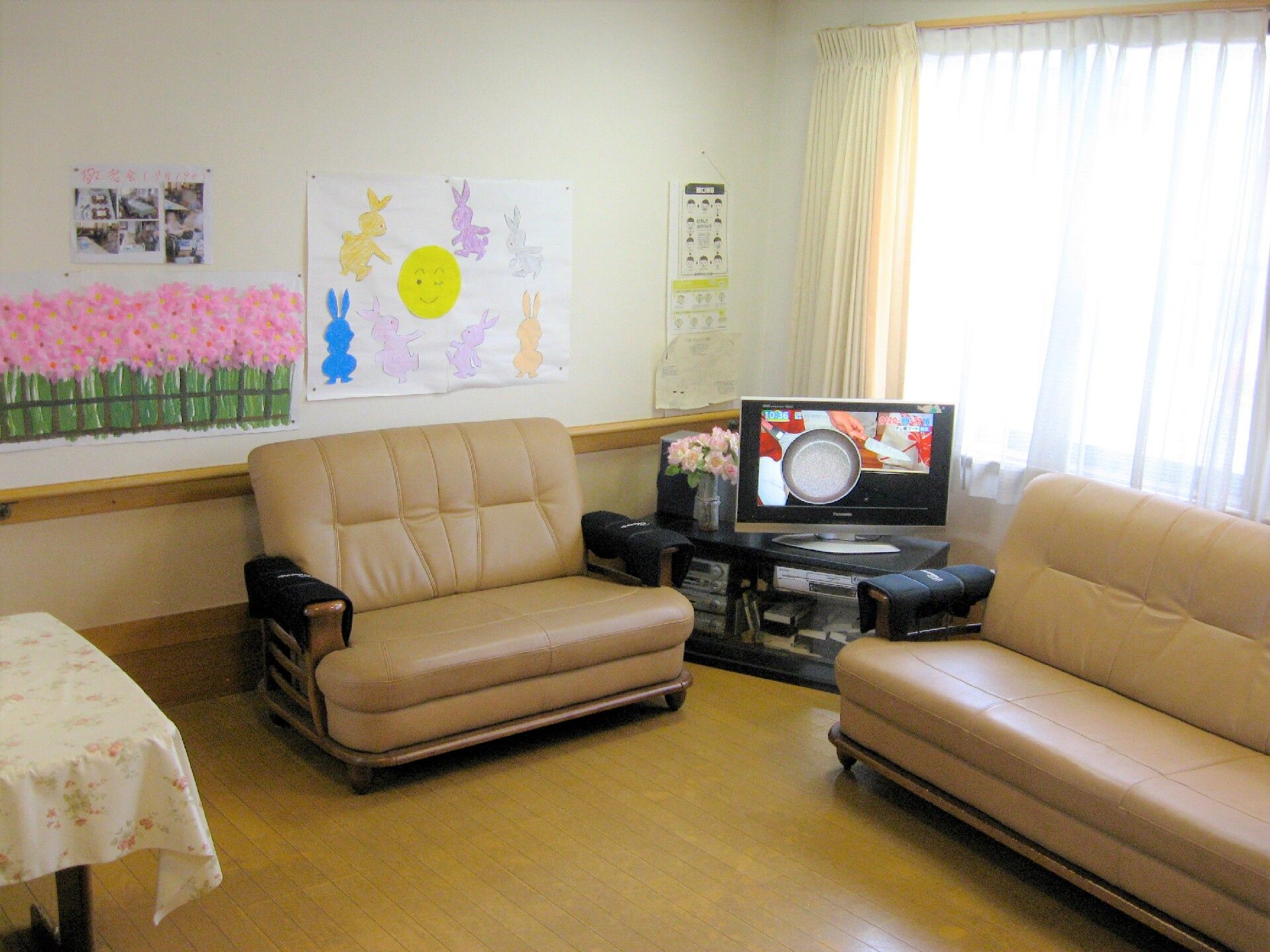 ソファやテレビが設置してあり、壁には入居者様の作品が貼ってあるリビング
