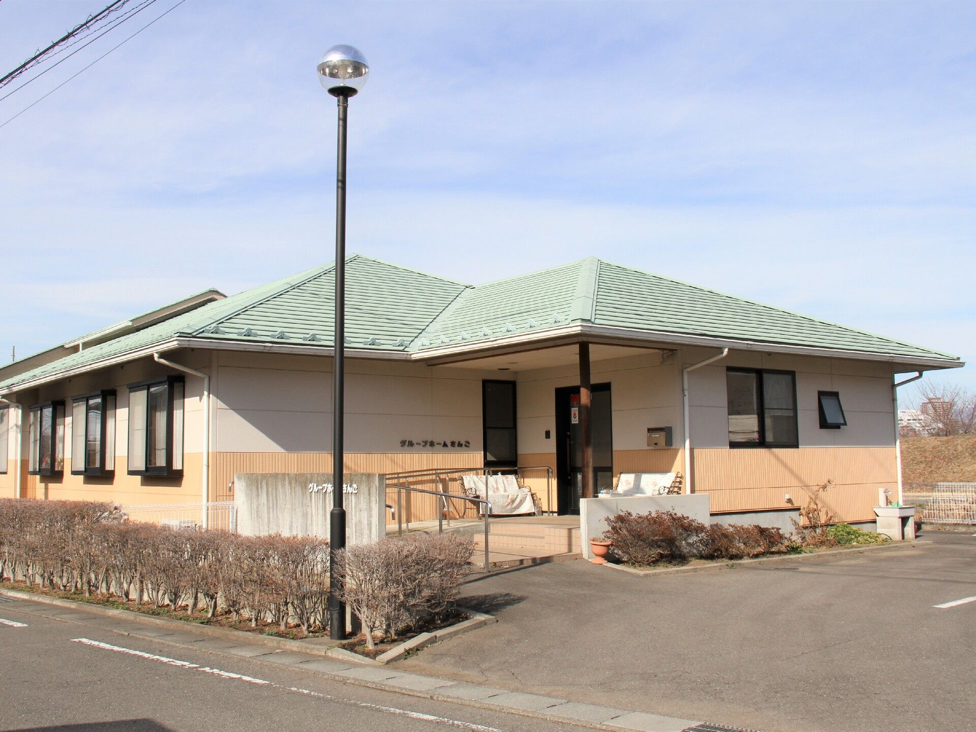 平屋建てで入り口ドアに続くスロープには手すりが設置されているグループホーム