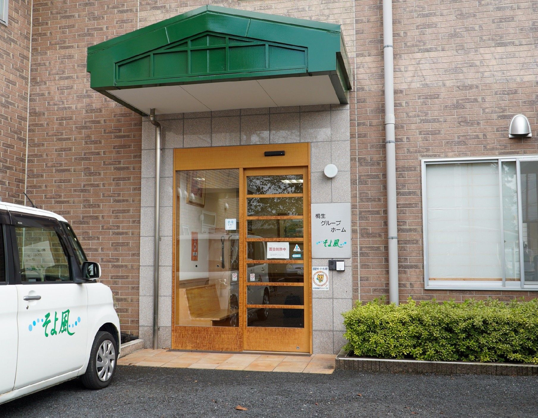 硝子戸の自動ドアが設置された玄関。玄関の横にはホームの名前が書かれている。