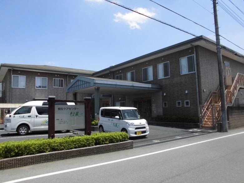 茶色の建物は２階建て。敷地内には広い駐車場があり、建物には屋外に避難用の階段が付いている。