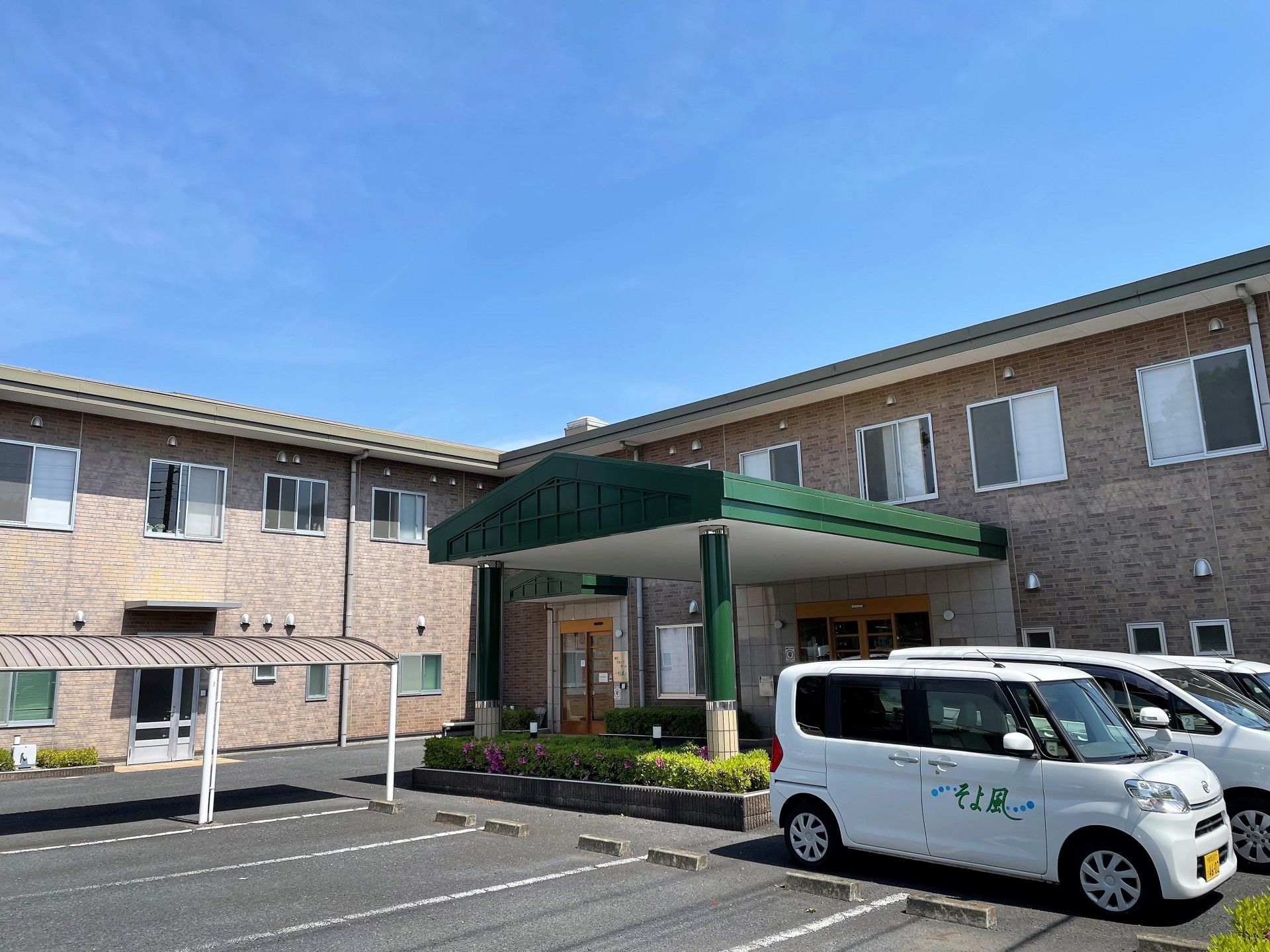 ２階建ての建物はブラウン系でまとめられていて、敷地内には広い駐車場もある。