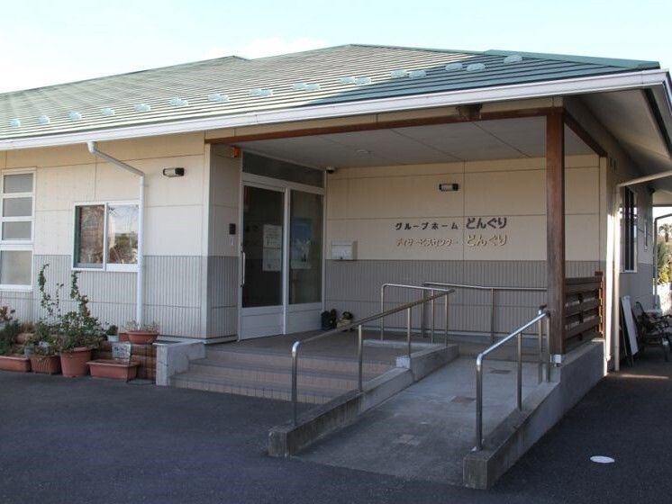 食卓についてスタッフが用意するお茶を待っている女性の入居者3人。