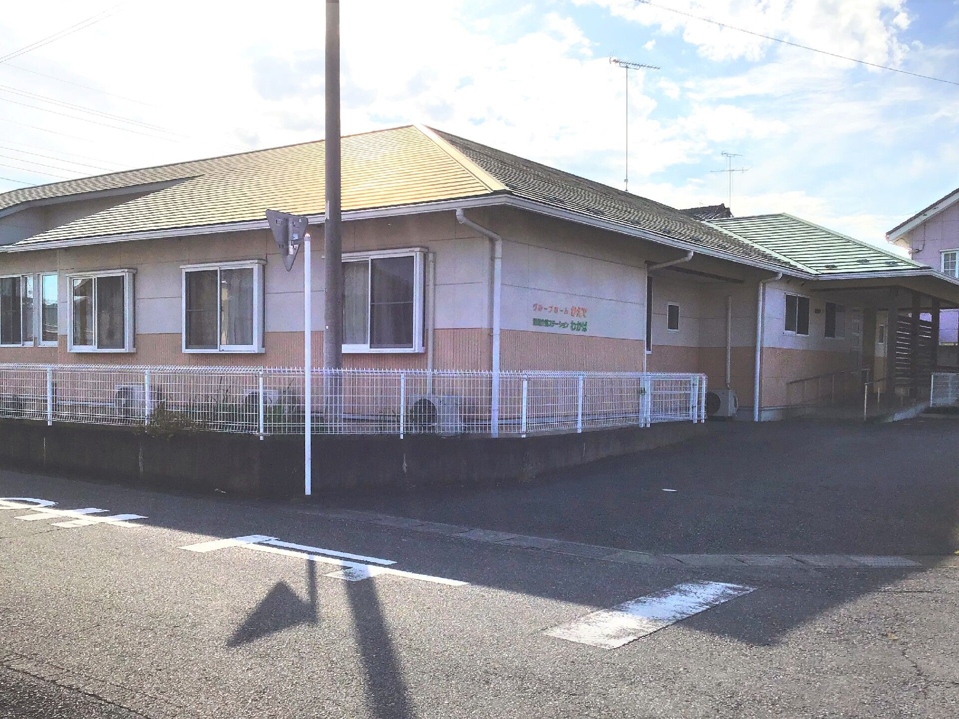 若い女性スタッフと高齢夫婦が並んで日当たりのいい芝生に座って談笑をしている。