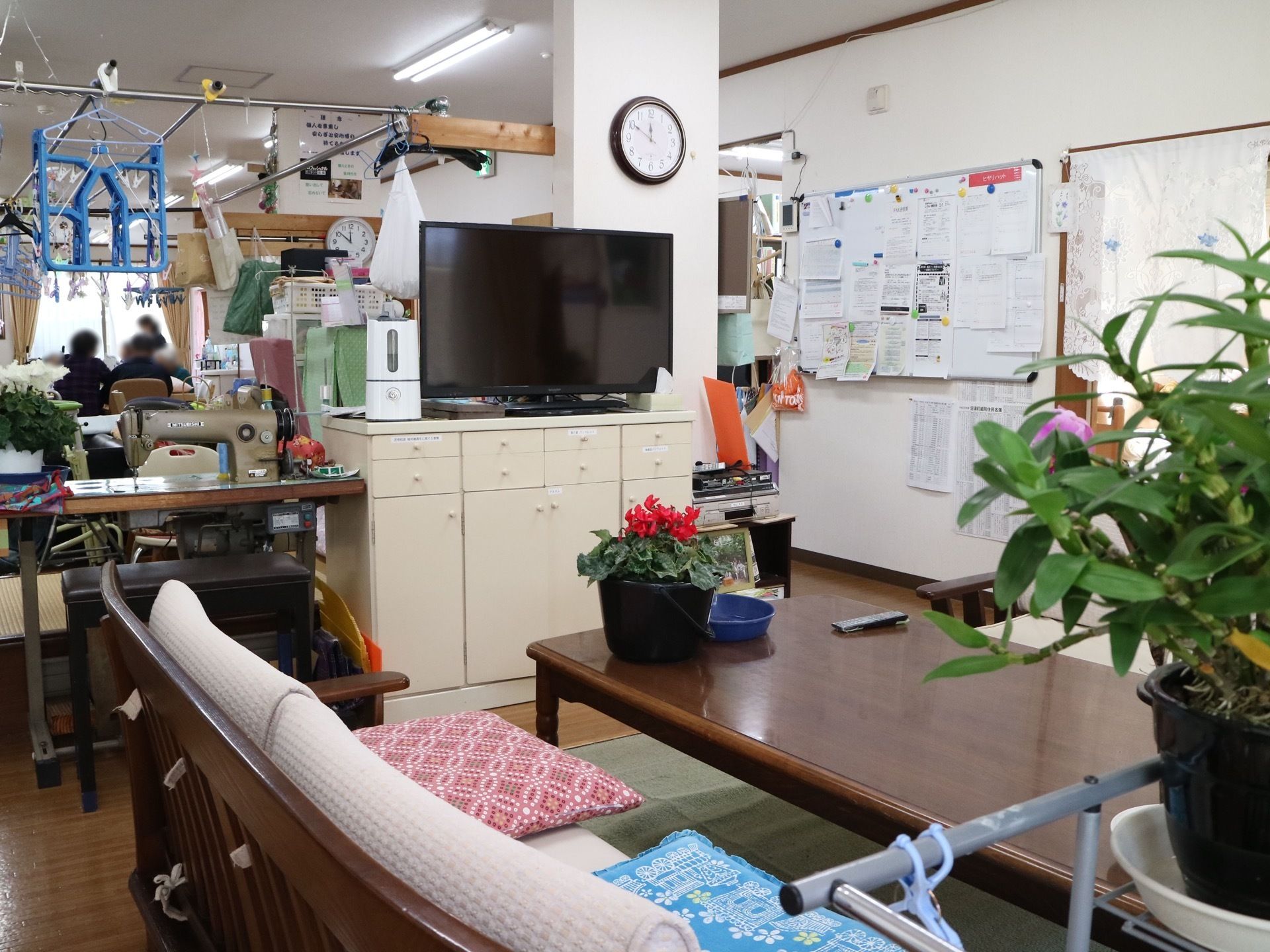 テレビやミシンが設置されているリビングである。廊下にある掲示板には、たくさんのプリントが貼られている。