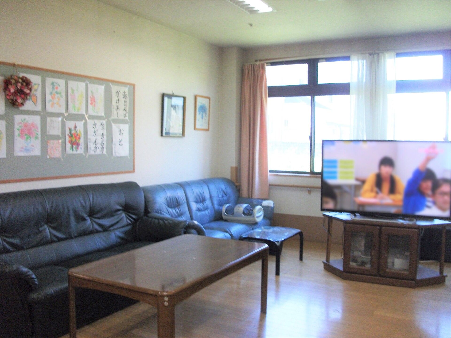平屋建ての建物のの玄関の前には花壇があり、それを囲むように手すり付きのスロープが設置されている。