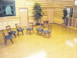 明るい色の床を敷いた木造の建物。天井の照明を床が反射している