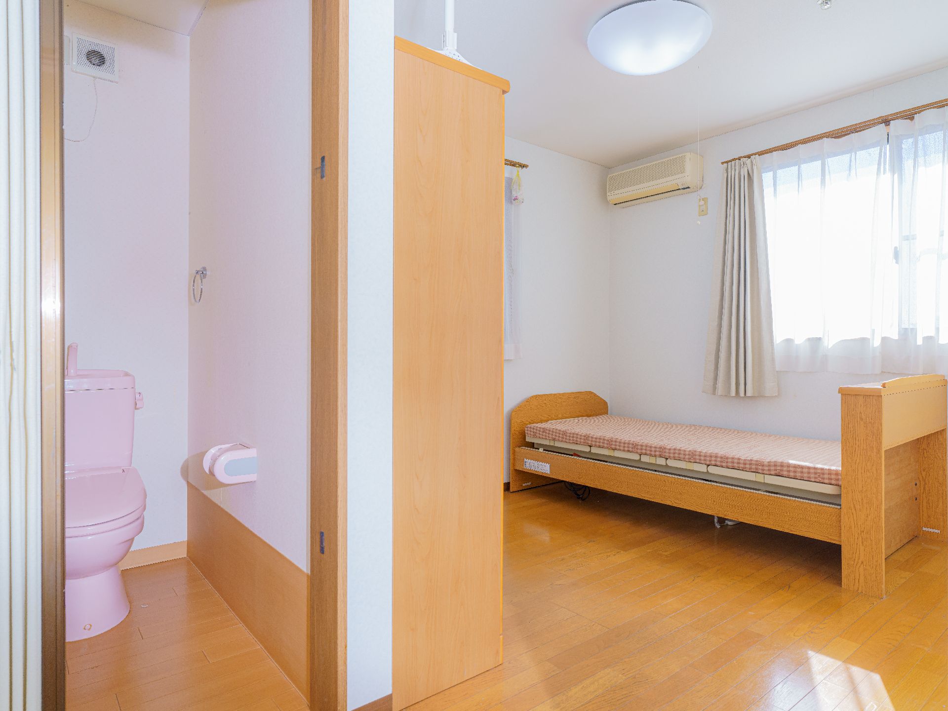 高齢者の方にタオルをかけてマッサージしているスタッフと振り返りながら会話する女性の様子