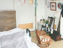 木のタンスが置いてある小さなワンルームタイプの部屋。籐のいすが置いてある様子