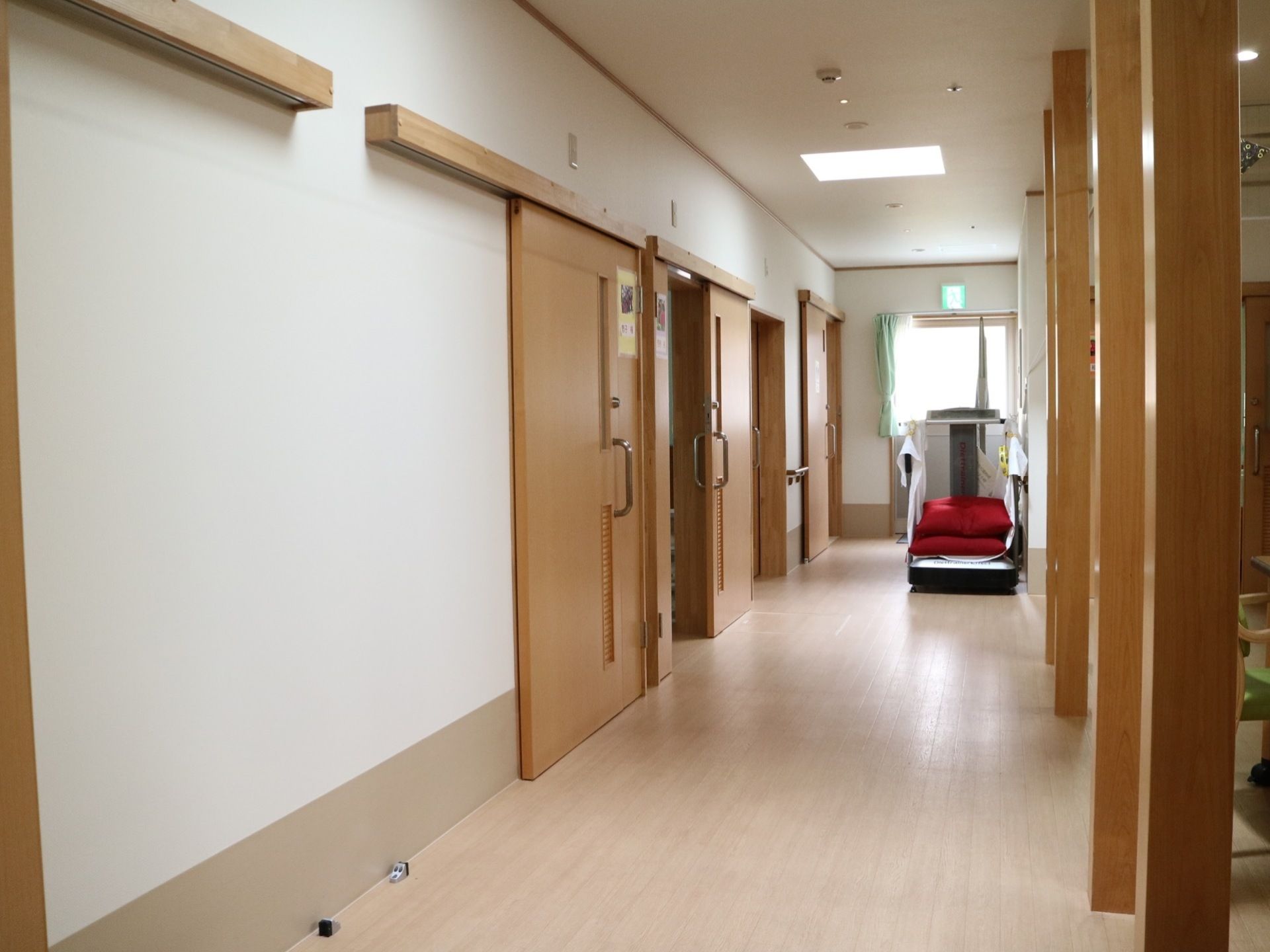 右奥に向かって廊下が伸びている。右手には柱が等間隔に立っている。左手には居室へ入る引き戸の扉が並んでいる。