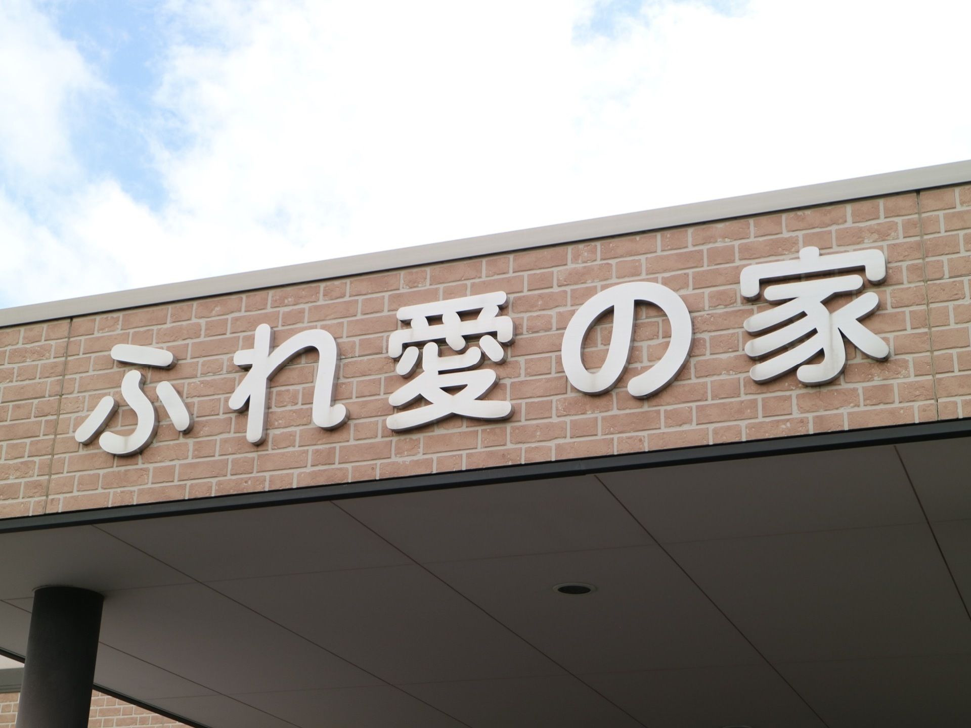 施設の入口にある玄関ポーチの屋根に作られた看板である。レンガが埋め込まれた屋根に、大きな文字で施設名が書かれている。